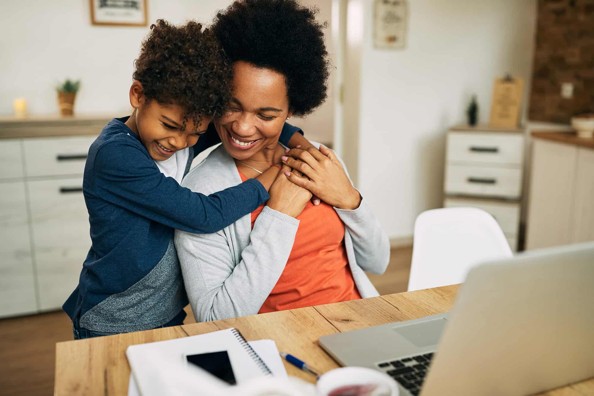 young son and mom at desk snuggling