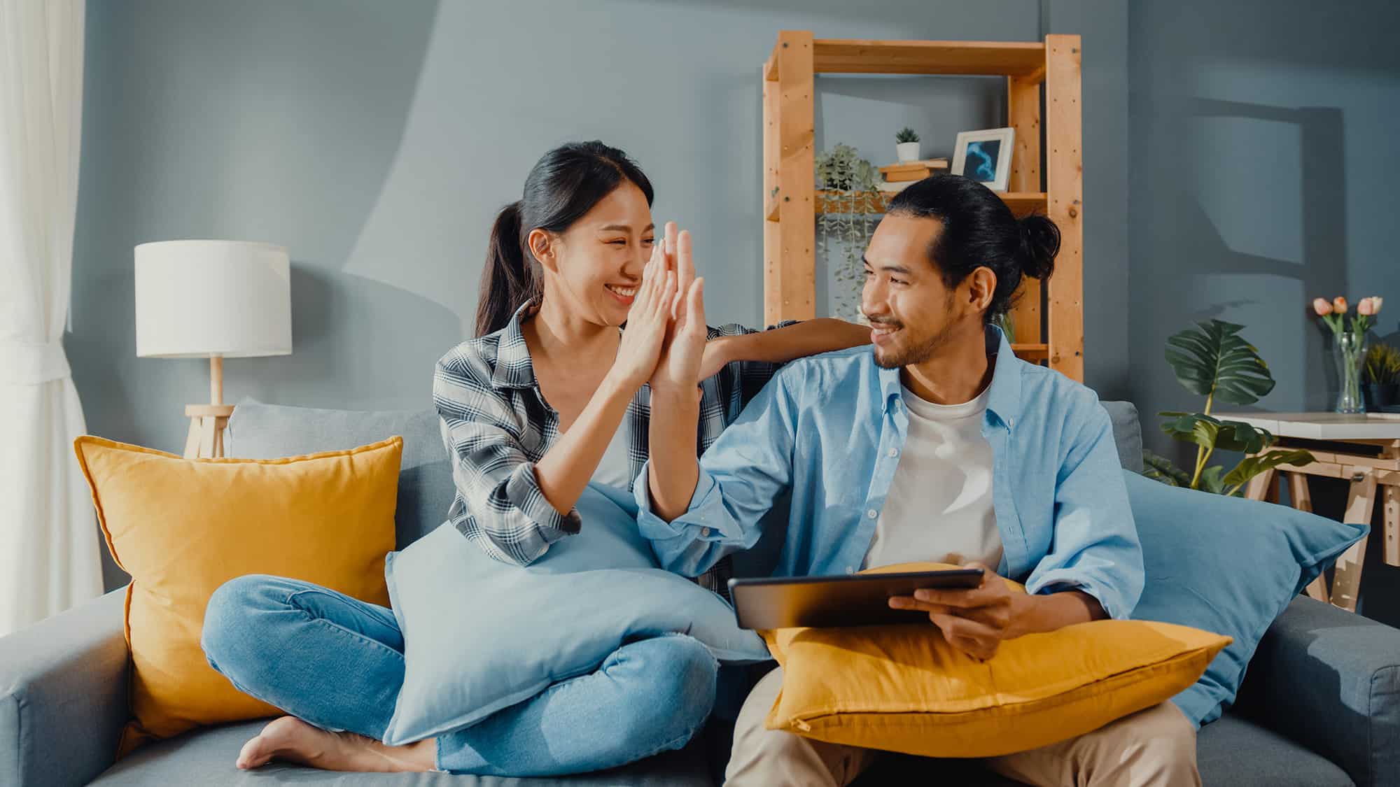 young couple on couch doing a high five